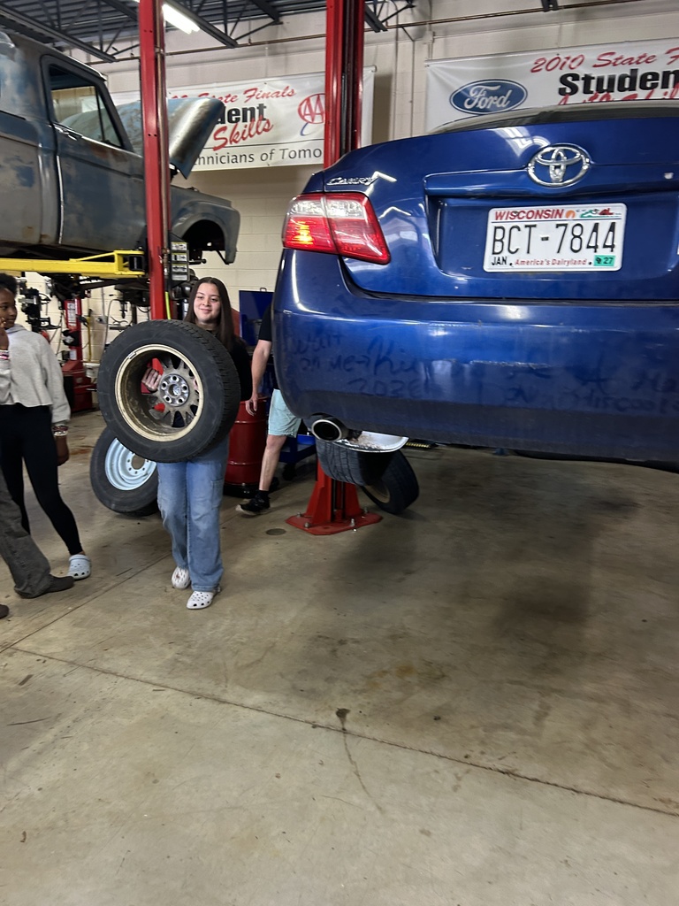 A Mitchell student walks with a car tire.