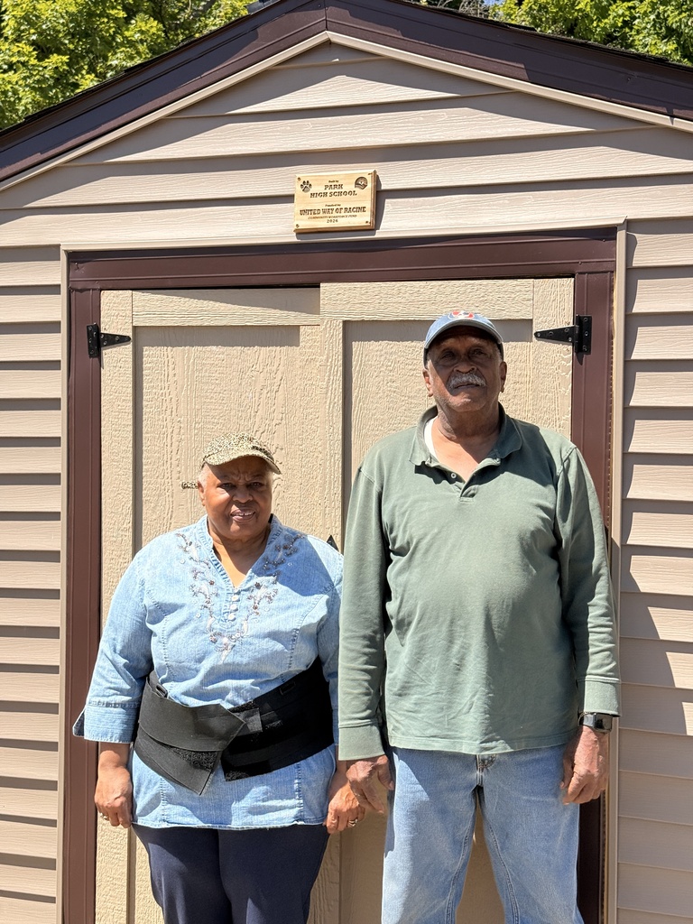 Two members of the community garden pose for a photo in front of the new shed.