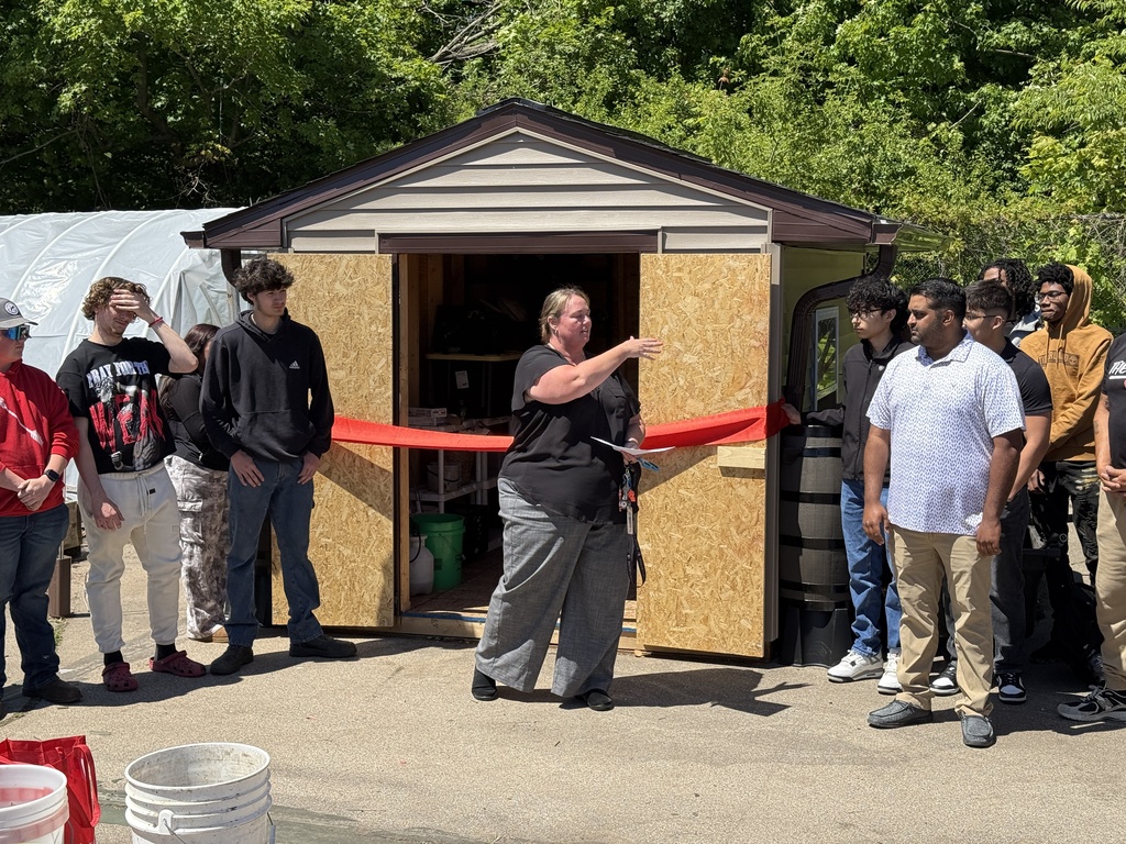 An instructor speaks in front of the new storage shed.