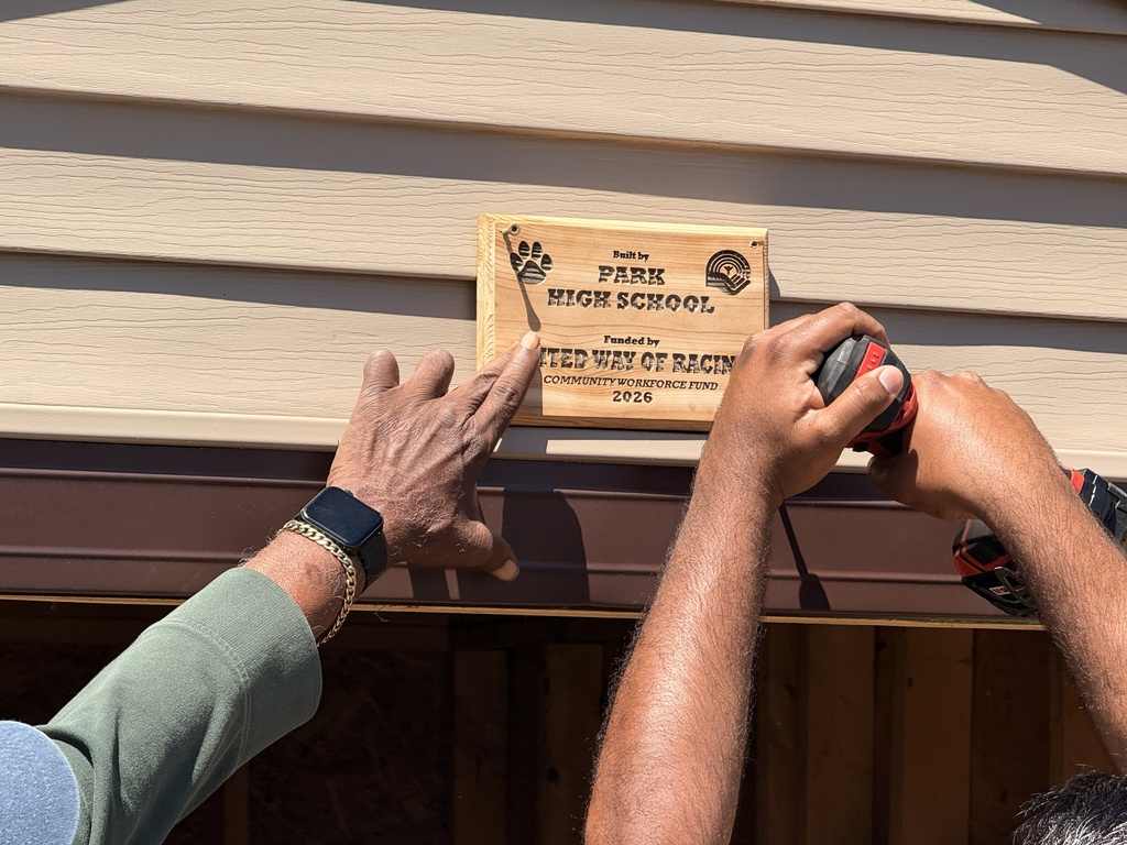 A commemorative plaque being installed above the door to the storage shed.
