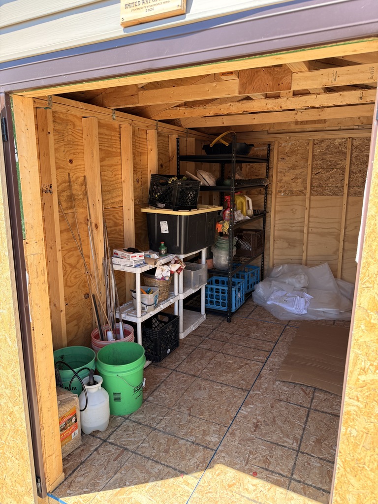 The inside of the storage shed. To the left are shelves for supplies.