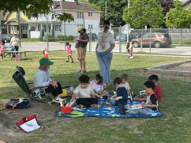 Teacher reading to students under a tree.