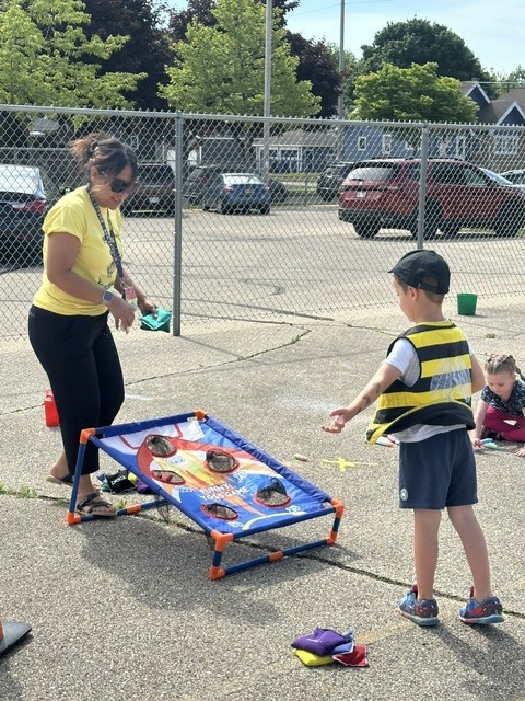Boy and female teacher playing cornhole.
