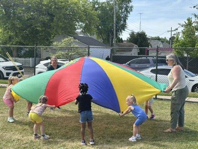 Teacher and students playing with parachute.