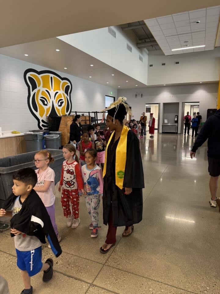 A senior walks with our kindergarten students through the halls of Jerstad.