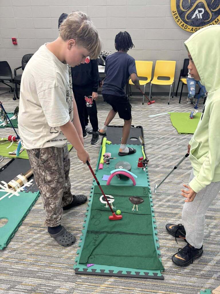 A student plays mini golf on one of the student created projects.