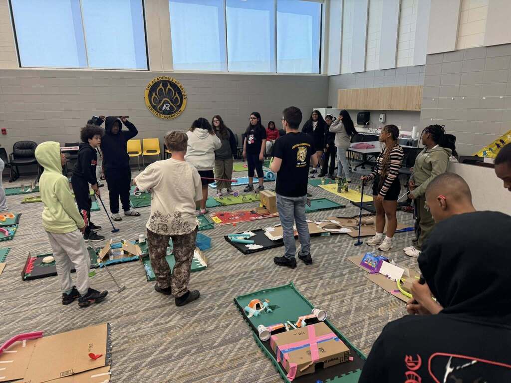 Students stand by their mini golf projects that they made.