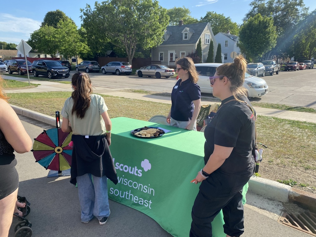 A family spins a prize wheel at the Girl Scouts table.
