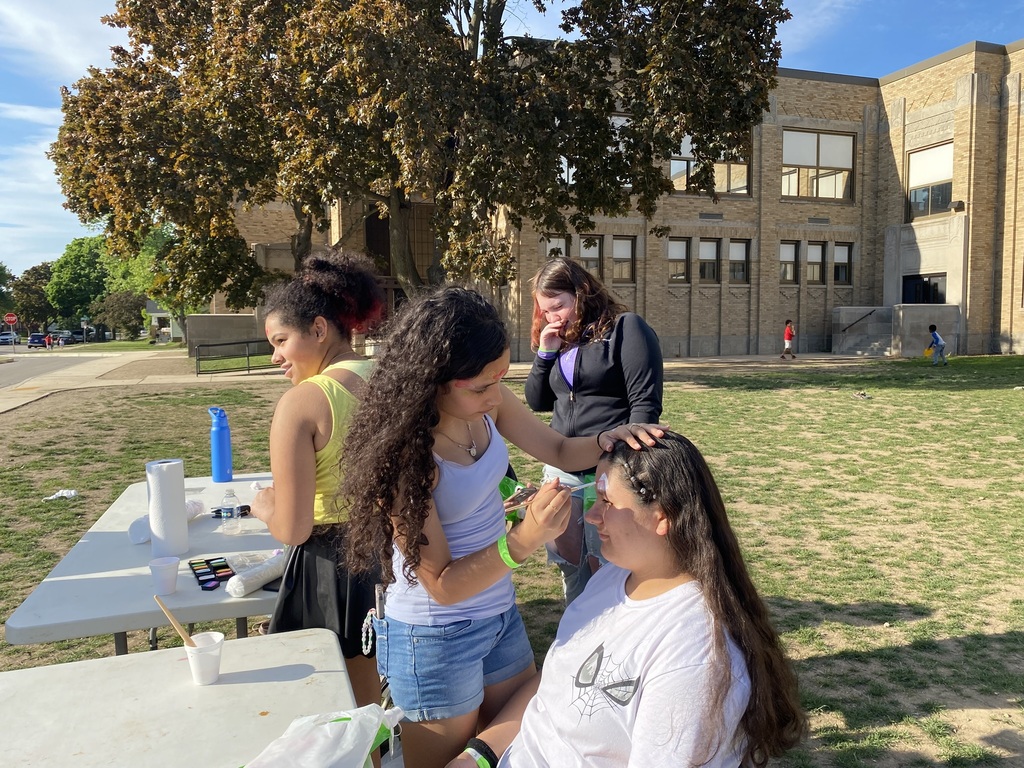A middle school girl paints the face of another middle school girl.