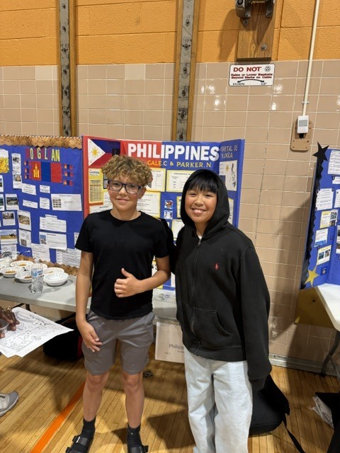 Two students pose for a photo in front of their project on the Philippines.