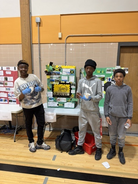 Three students pose for a photo in front of their project on Jamaica.