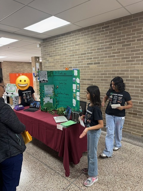 Two students give a presentation to a community member about their project.