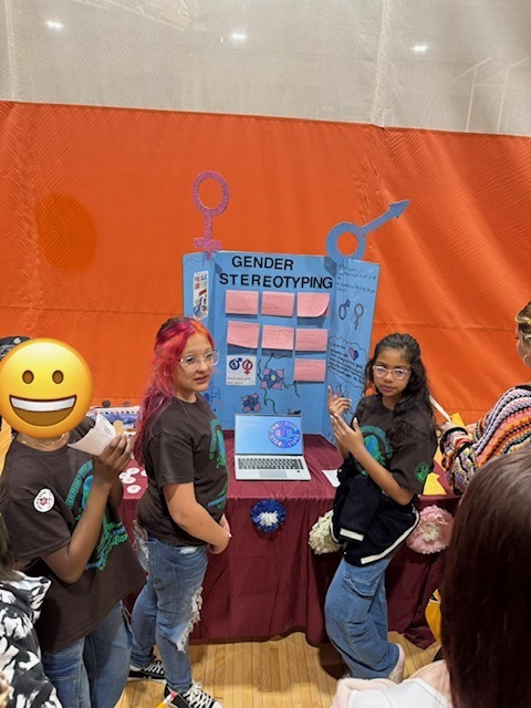 Two students giving a presentation in front of their project on Gender Stereotyping.