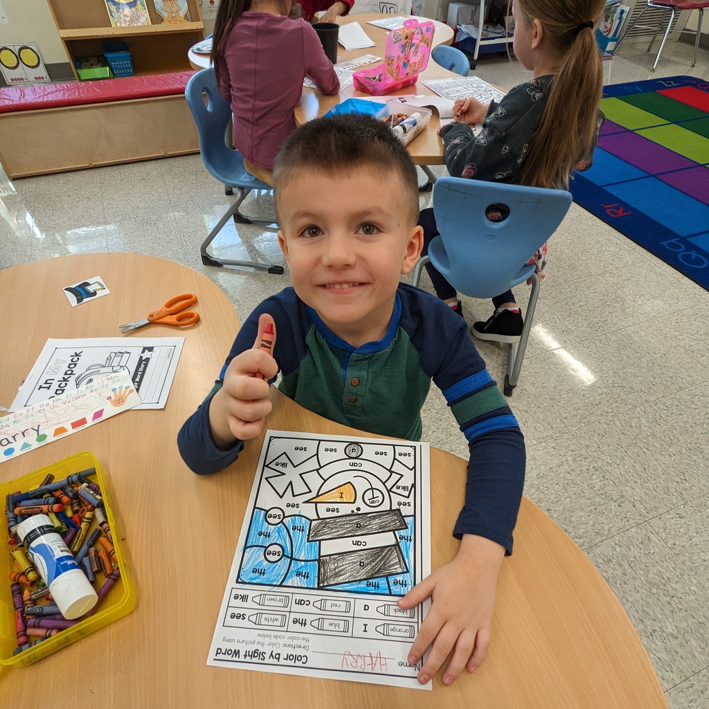 A kindergarten boy giving a thumbs up with a smile.