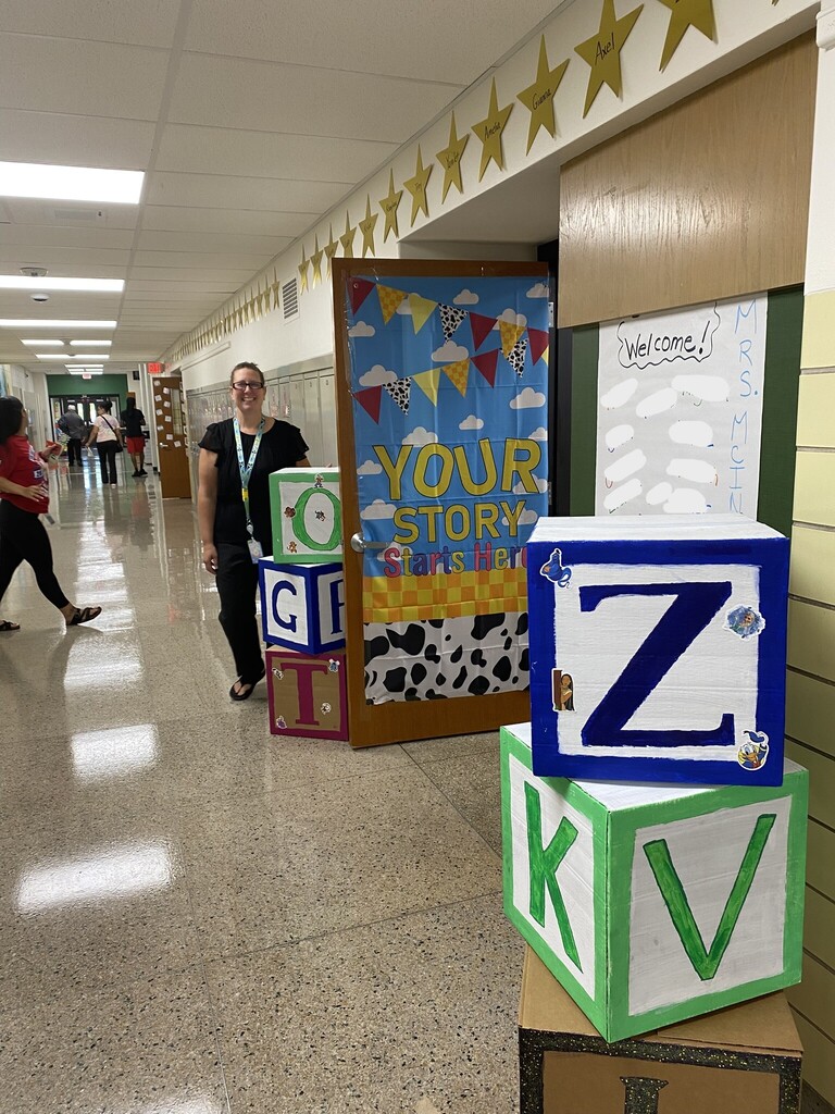 Kindergarten teacher stand outside of her classroom door, decorated after Toy Story. 