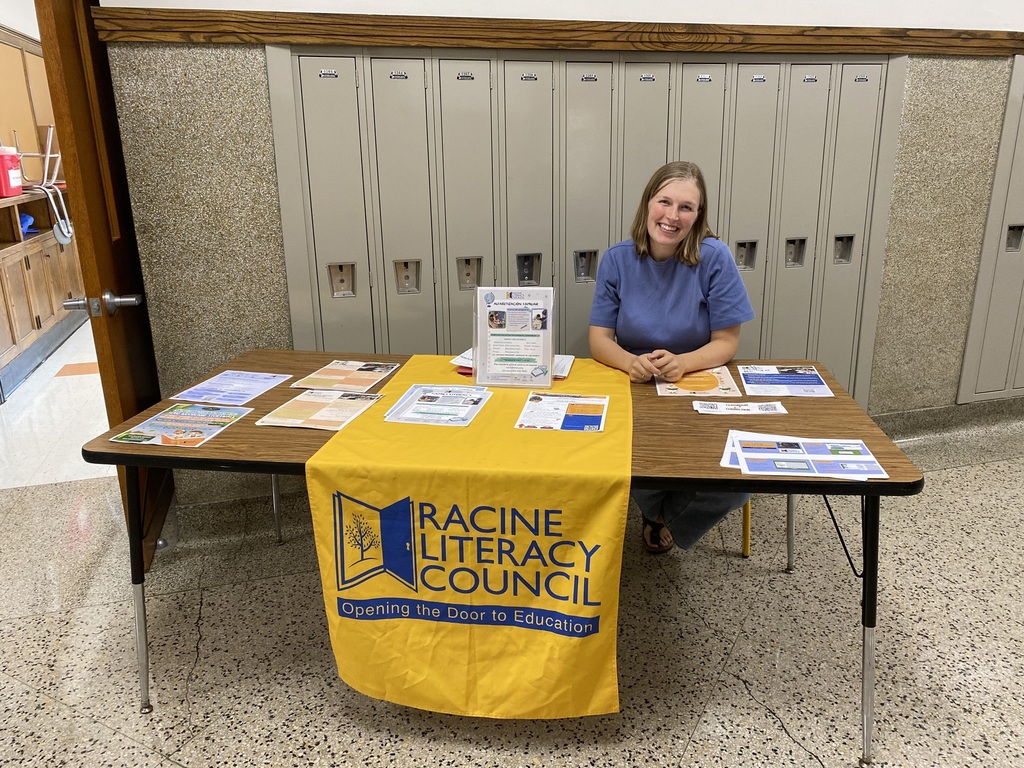 One adult woman sitting behind a table advertising Racine Literacy Council.