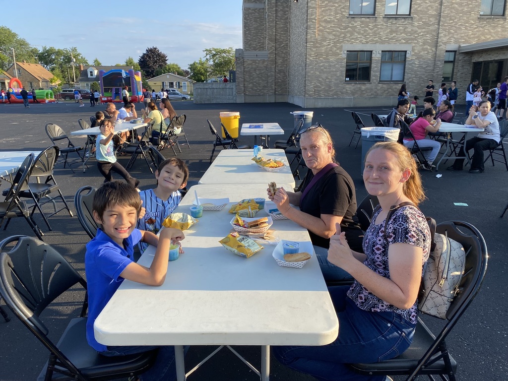 A family of four sitting at a table outside eating.