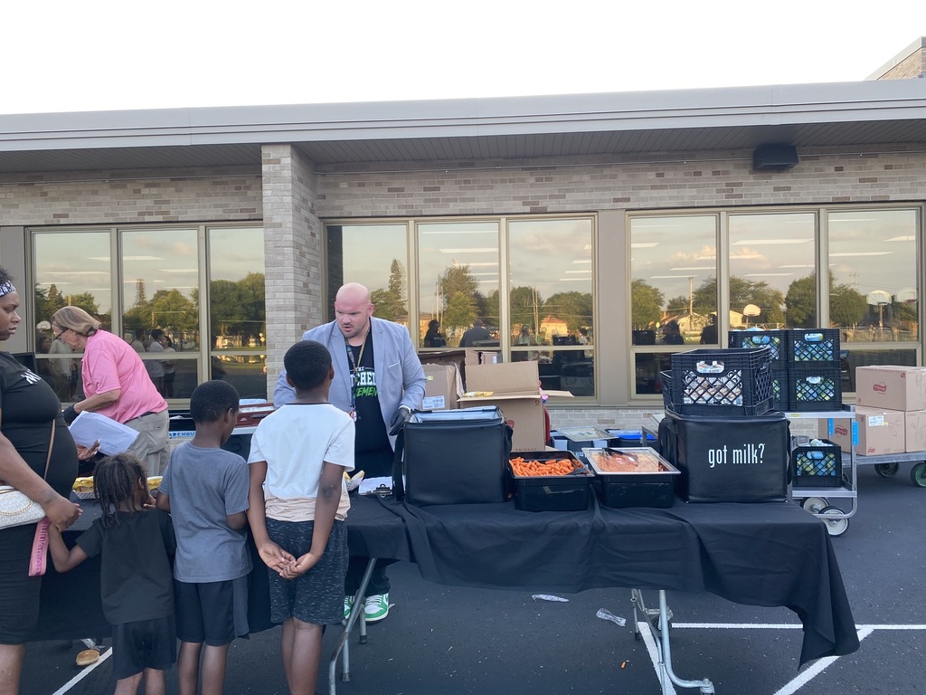 3 young boys waiting in line for food. Mitchell's principal, Mr. Miller, serves food.