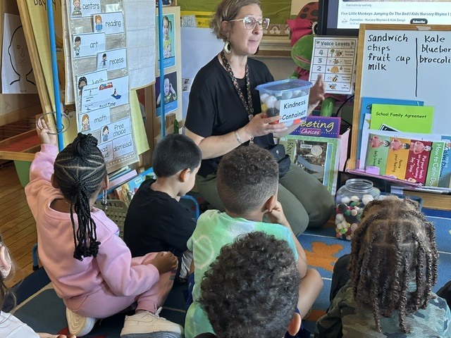 Teacher and K4 students add to the classroom 'Kindness Container'