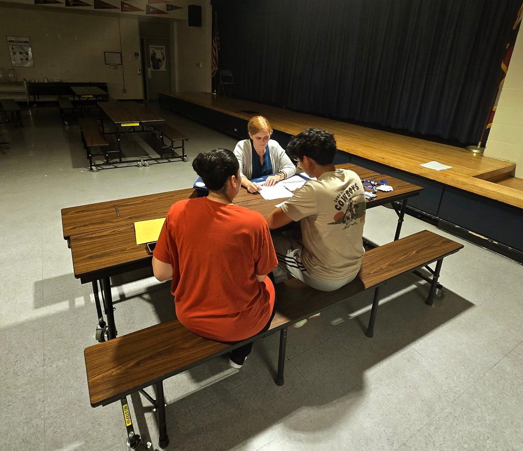 Mom and child are sitting across from bank personnel as they open the students first savings account