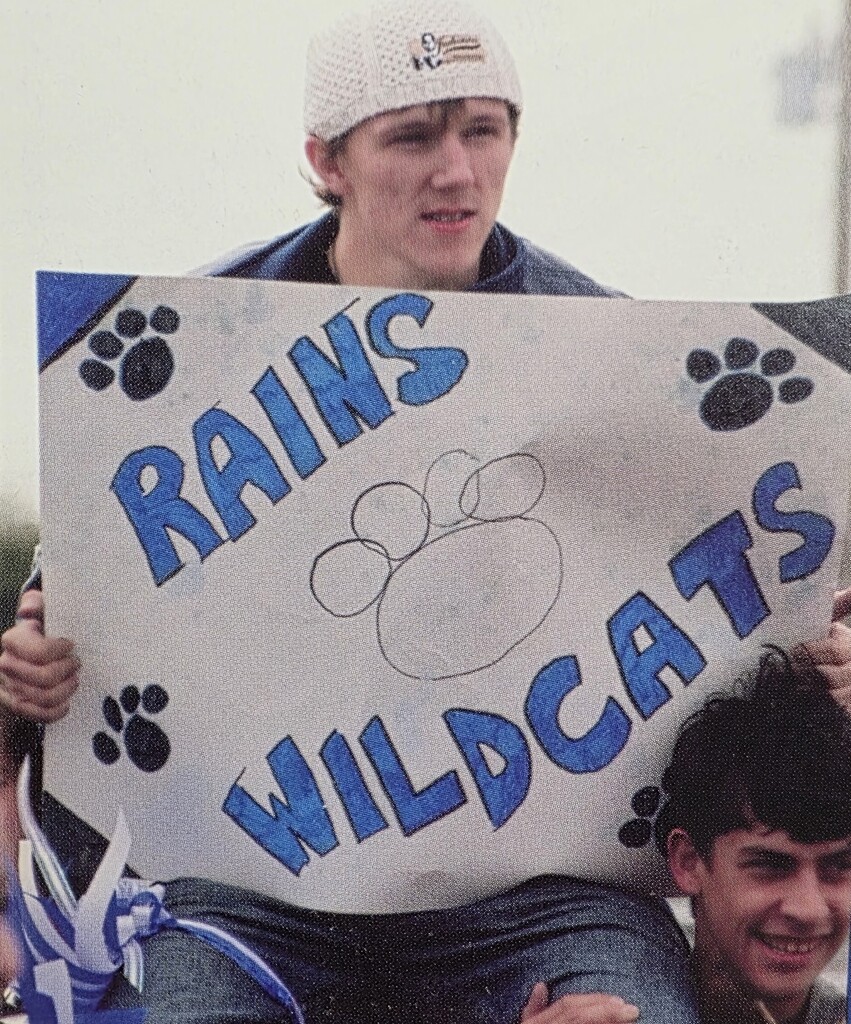 Young boy holding a sign that says rains wildcats
