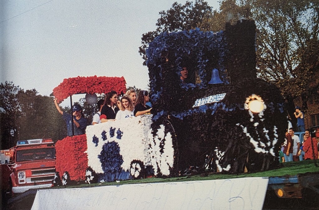 Parade float decorated like a train with a blue wildcat paw