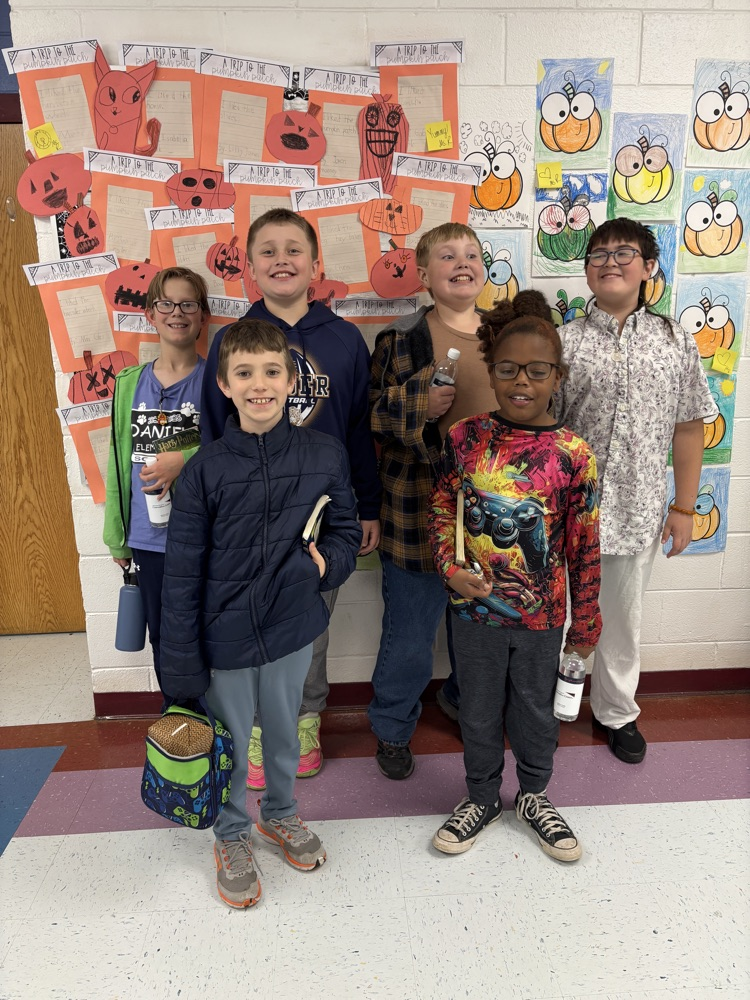 six boys that attended the math field day, standing in front of pumpkins, smiling and happy