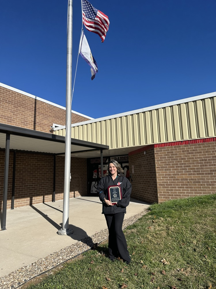 principal with award in front of school 