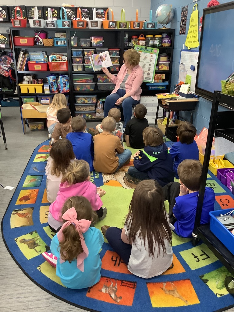 Dr. Hutchens reads a story to the Kindergarten class. They listen quietly on the rug. 