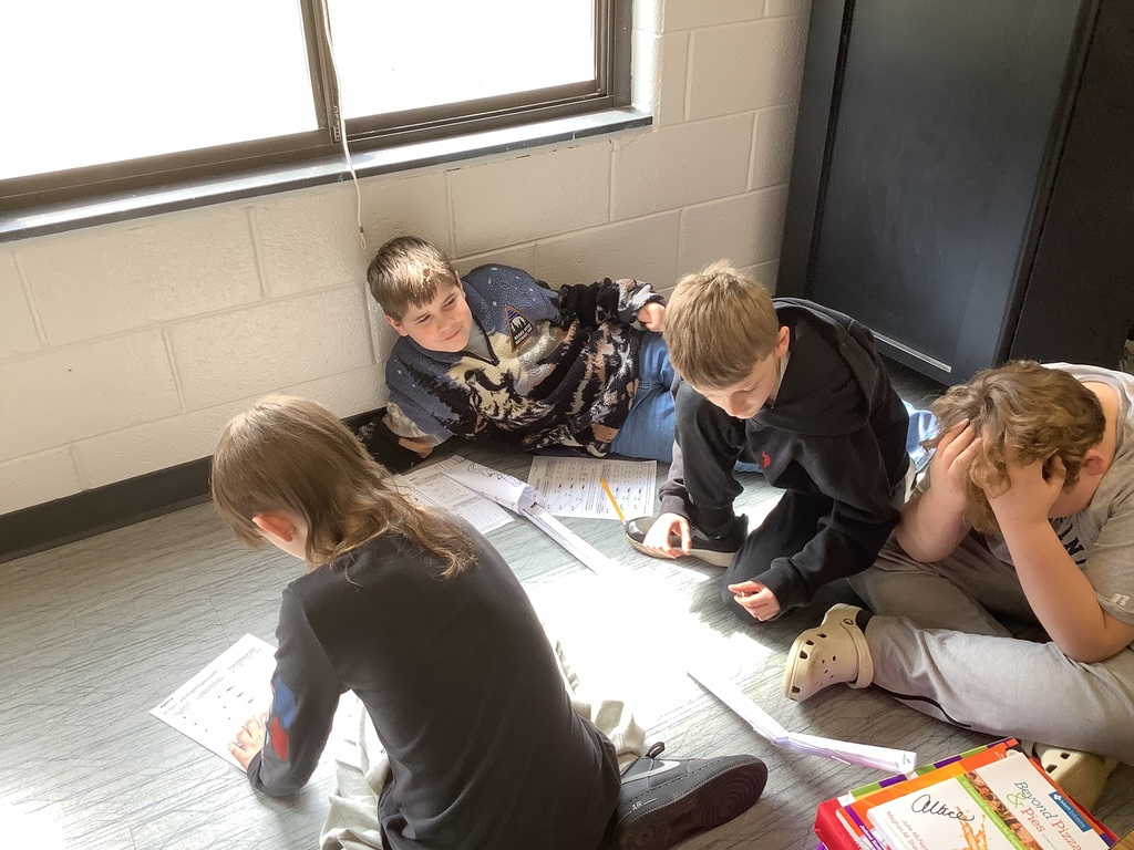 4th grade students are sitting in the floor working on energy and energy transfer.