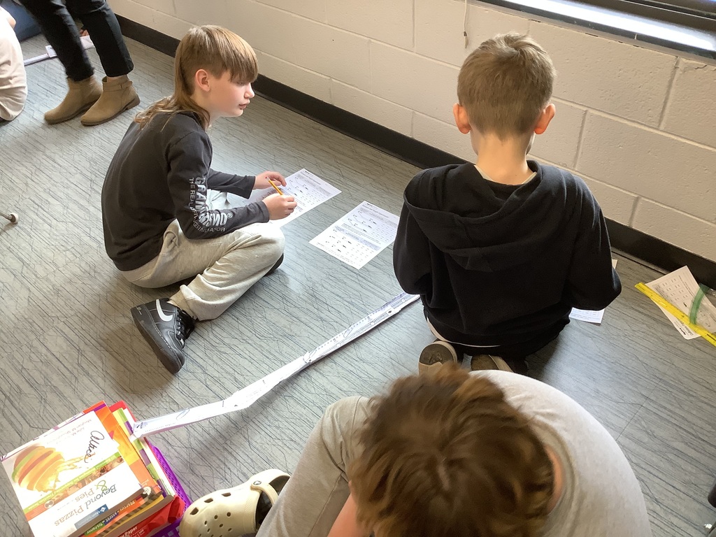 4th grade students are sitting in the floor working on energy and energy transfer.