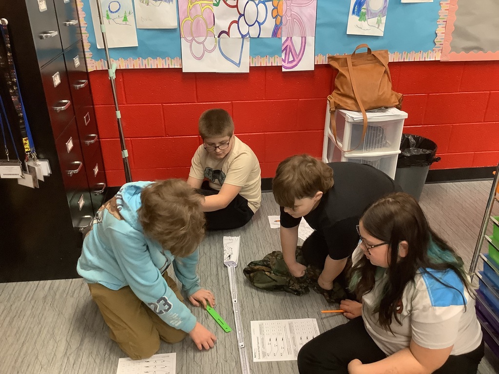 Students are rolling marbles down their paper ramp.