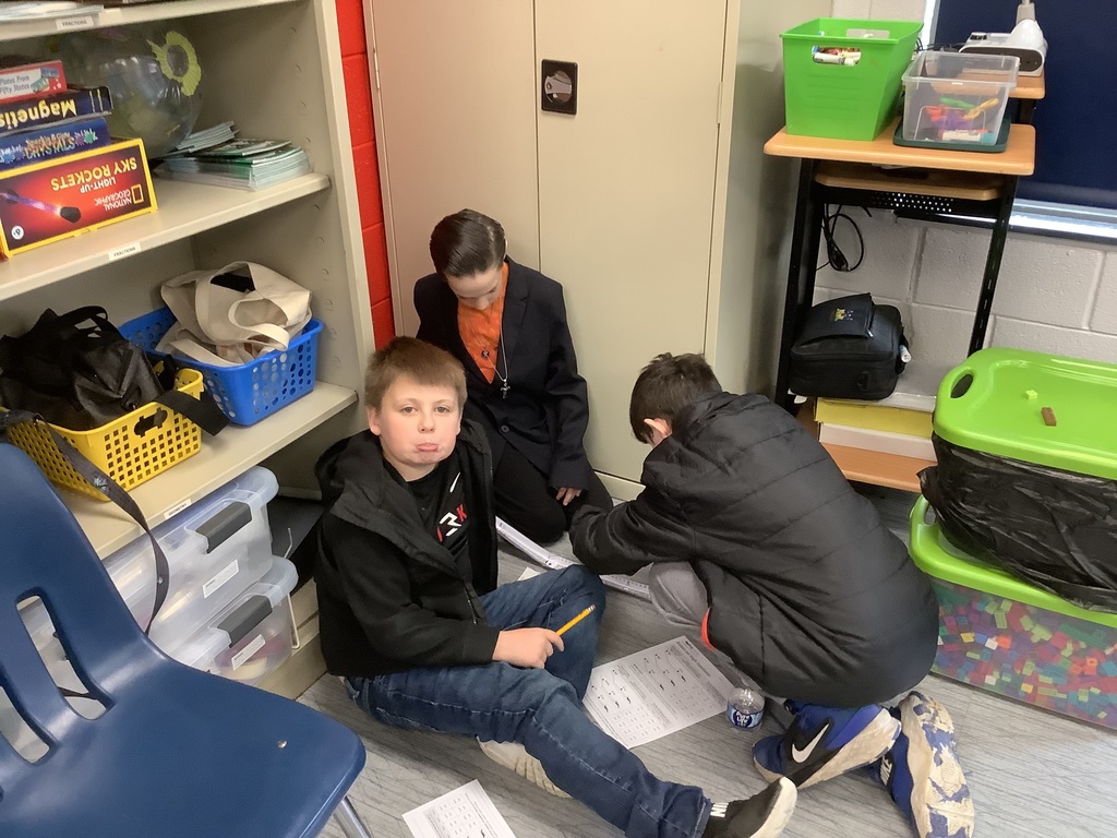 4th grade students are in the floor building a ramp out of paper.