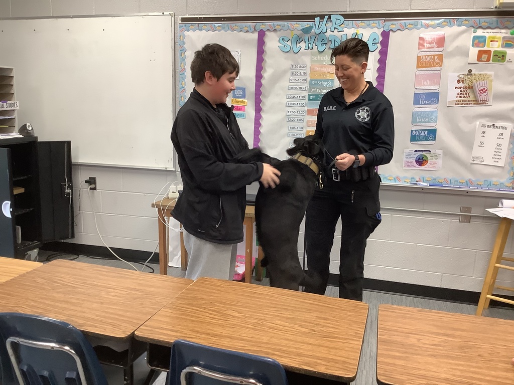 Police dog jumped onto 5th grade student. They are smiling. 