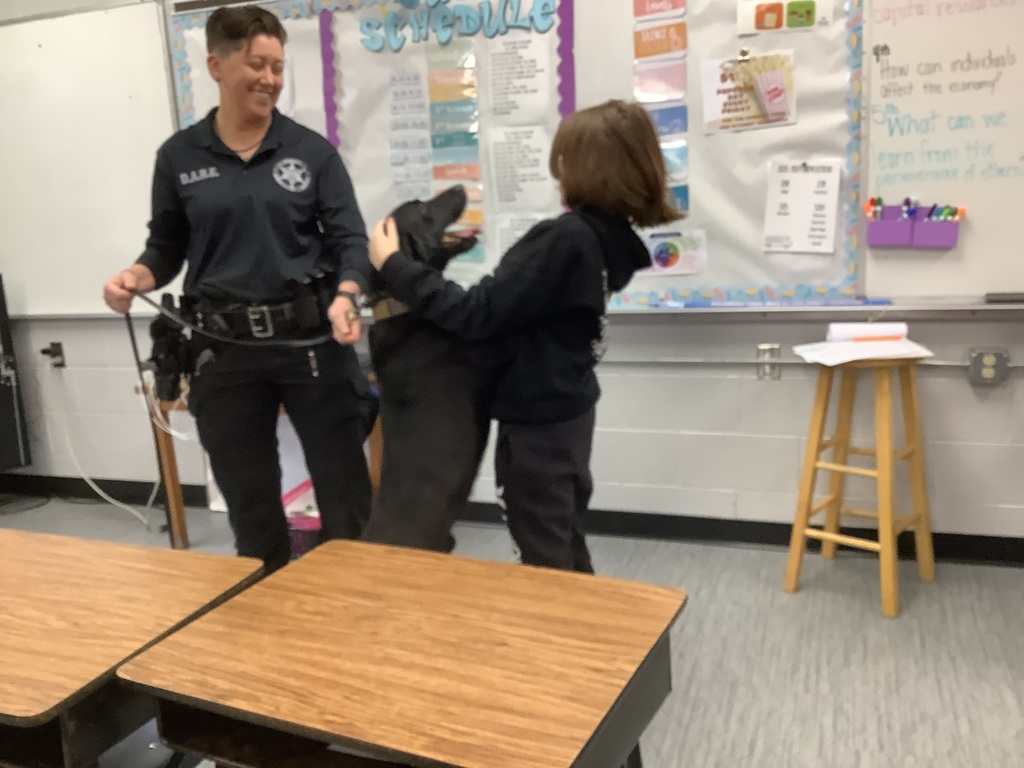 Police dog jumped onto 5th grade student. They are smiling. 