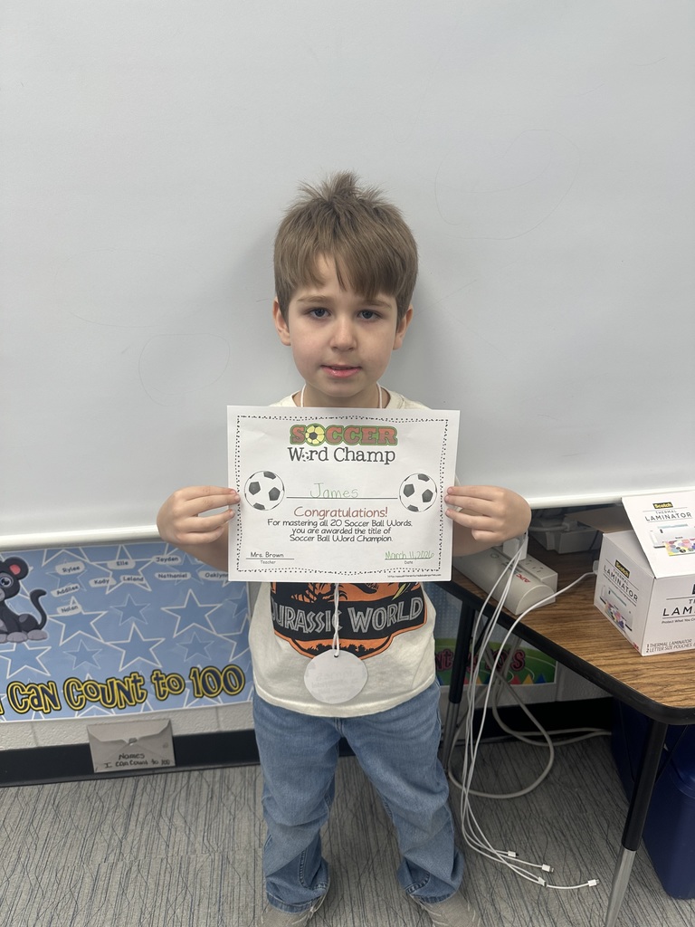 Student is holding his soccer word champ certificate and smiling. 