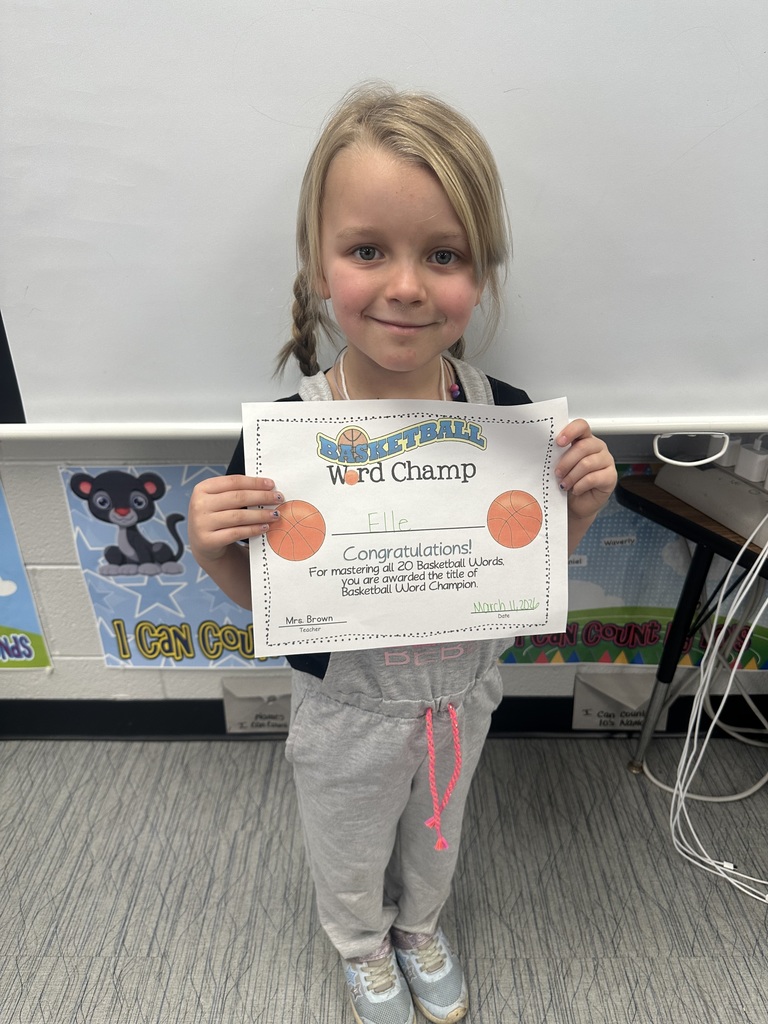 Student is holding her basketball word champ certificate and smiling.