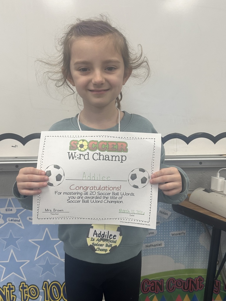 Student is holding her soccer word champ certificate and smiling. 