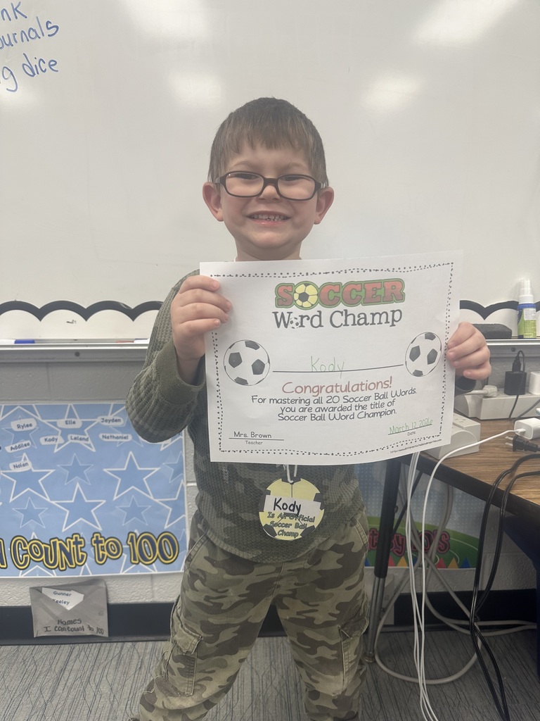 Student is holding his soccer word champ certificate and smiling. 