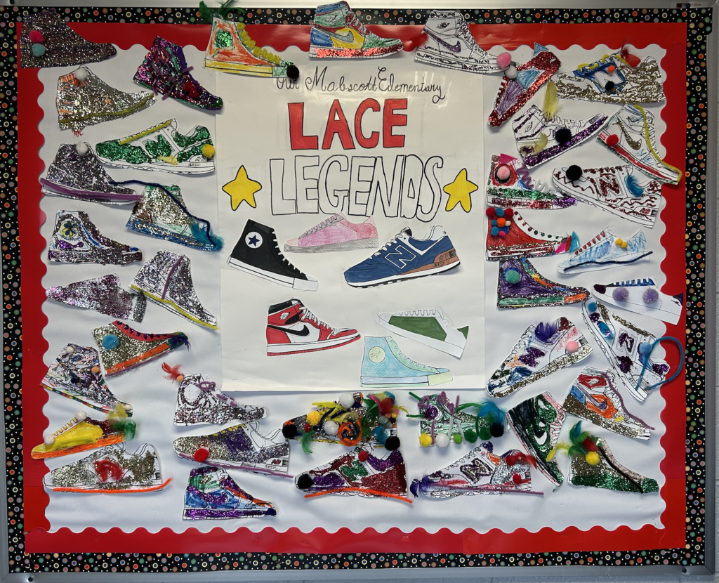 A colorful school bulletin board titled “Lace Legends” at Mabscott Elementary, featuring dozens of student-decorated paper sneakers covered in glitter, pom-poms, feathers, and bright designs arranged around the border.