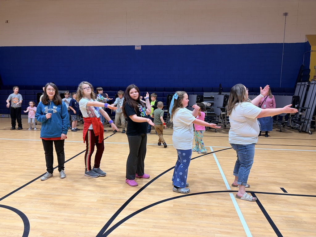 A line of girls have their arms out in front of them dancing. 