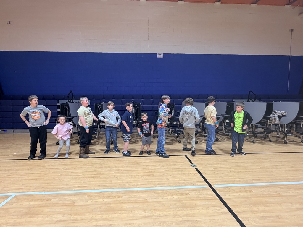 A line of boys have their hands on their hips dancing. 