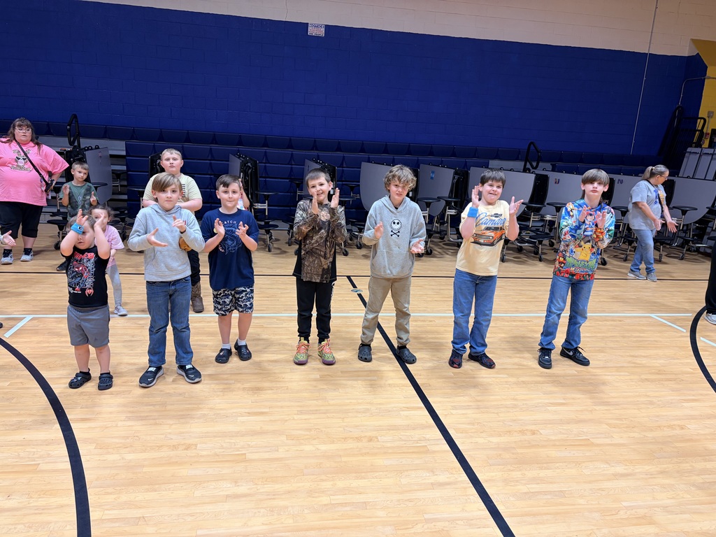A line a boys are clapping their hands dancing to music.
