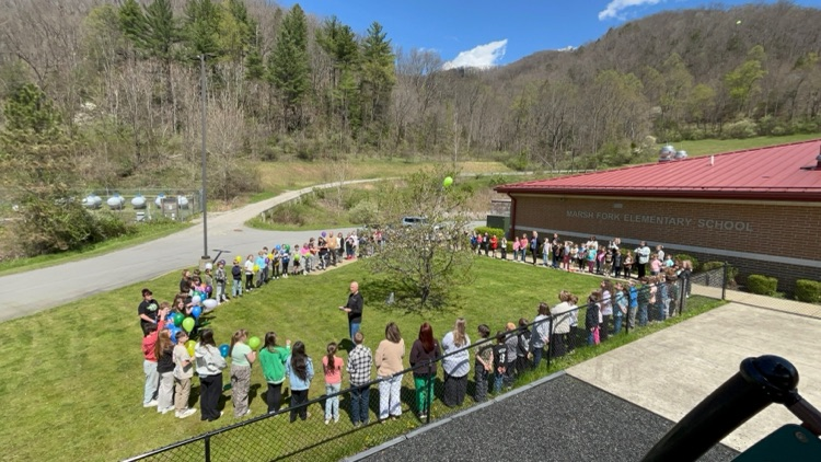 Students standing around the UBB memorial tree, while Mr. Dye leads the memorial ceremony .