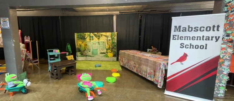 booth set up with green frogs and flower backdrop