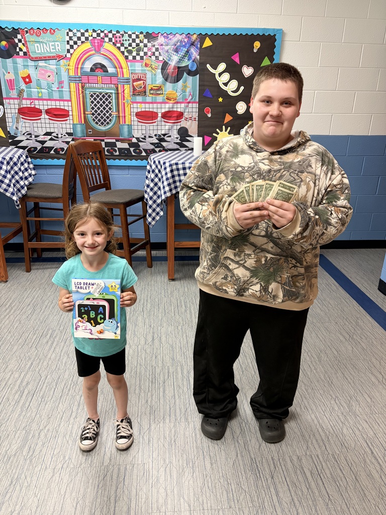 A kindergarten girl is holding a gift she can draw on. A 5th grade boy is holding cash.