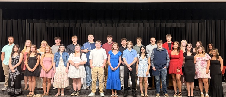 10th grade students who were inducted into the national honor society standing on the stage in the auditorium
