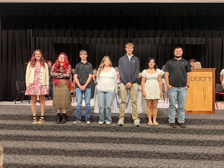 a senior student and 6 11th grade students who were inducted into the national honor society standing on the stage in the auditorium