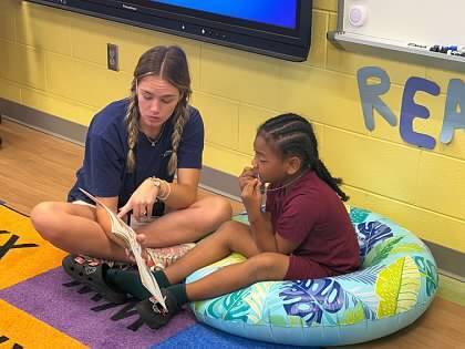 Energy Express teacher reading with a student on the floor. 