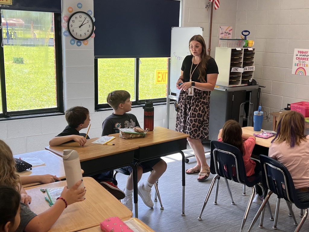 A female teacher leading a lesson while students listen intently.